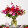 Pink and red roses, blush stock, carnations with greenery in a glass
