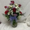 Mixed bouquet of red roses, white blooms, and purple flowers in a glass vase