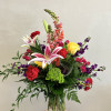 Mixed bouquet with lilies, roses, carnations, and snapdragons in a glass vase