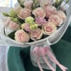 Bouquet of pale pink roses and lisianthus wrapped in paper with a pink ribbon