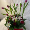 A beautiful garden of tulips, lilies, baby's breath, and red roses. A