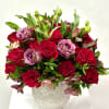 Red roses and pink lisianthus in a textured white vase