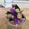 Small bouquet of white roses with purple ribbon in a clear container