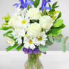 White roses and daisies with blue irises in a glass vase