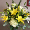 Yellow lilies and white roses in a vase with pale hydrangea