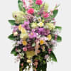 Tall standing floral spray with pink and yellow flowers and a ribbon