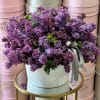 Bouquet of purple lilacs in a white hatbox with a ribbon