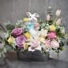 A charming spring arrangement filled with soft pastel blooms and nestled around