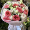 Pink and white rose bouquet wrapped in pale pink paper with a white ribbon