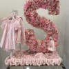 Pink floral number display with a baby dress and gift items