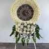 White rose funeral wreath with a clock centerpiece on a stand
