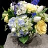 A lovely mix of blue hydrangea, yellow roses, white tulips, and royal