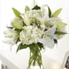 White lilies and hydrangeas arranged in a clear glass vase