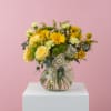A bright mix of yellow roses, gerbera daisies, and fresh greenery in