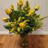 Tall arrangement of yellow roses with yellow filler in a clear glass vase