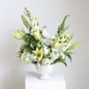 White and pale yellow lily arrangement in a white vase