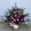 Mixed pink, purple, and blue floral arrangement in a white vase