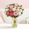 Pink and white mixed bouquet in a clear glass vase with a pink ribbon