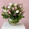 Arrangement of pink and white tulips with tiny pink blossoms in a round clear glass vase