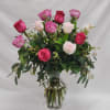 A vase full of a dozen roses in various shades of pink