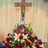 Red roses and white lilies arranged around a crucifix and patriotic egg centerpiece