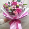 Pink rose bouquet with mixed blooms wrapped in pink paper and ribbon