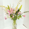 Pink lilies in a tall glass vase with yellow branching accents