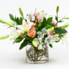 Bouquet of white lilies, peach roses, and white alstroemeria in a glass vase