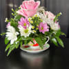 Pink rose and white daisy bouquet in a teacup on a saucer