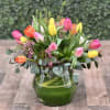 A colorful assortment of tulips in a glass vase with greens and