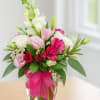 Pink and white mixed bouquet in a clear glass vase with a bright ribbon