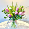 Vibrant tulips in warm, radiant hues are paired with lush greenery for