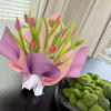 Pink tulips wrapped in pink and purple paper on a table