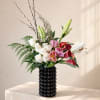A refined arrangement of roses, lilies, and tulips with fresh greenery in