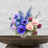 Bouquet of purple, pink, and blue flowers in a white vase