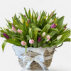 A cheerful basket filled with colorful, seasonal, tulips and lush greenery, bringing