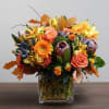 A vibrant autumn-inspired floral arrangement featuring warm shades of orange, golden yellow