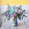 A uniquely shaped vase with light luscious flowers that smell and look