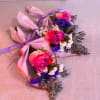 Three small pink rose bouquets wrapped in pastel paper with purple ribbon