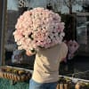 Large bouquet of pale pink roses held in front of a shop window