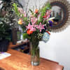 Tall mixed bouquet in a clear glass vase with pink lilies and assorted blooms