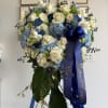 Heart-shaped standing wreath of white roses and blue hydrangeas with blue ribbon on an easel