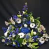 Blue and white floral arrangement with a blue glass candle holder in the center