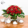 Red rose arrangement in a clear glass vase on a wooden table