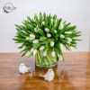 White tulips in a clear glass vase with two small bird figurines
