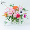 Mixed pink, white, and orange flowers arranged in a clear glass vase