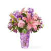 Pink lilies and purple flowers in a purple glass vase