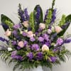 Lavender and pink floral arrangement in a white pedestal vase