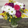 Bouquet of white daisies, pink carnations, and yellow filler in a glass vase