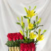 Red roses and yellow lilies arranged in a black box with chocolates